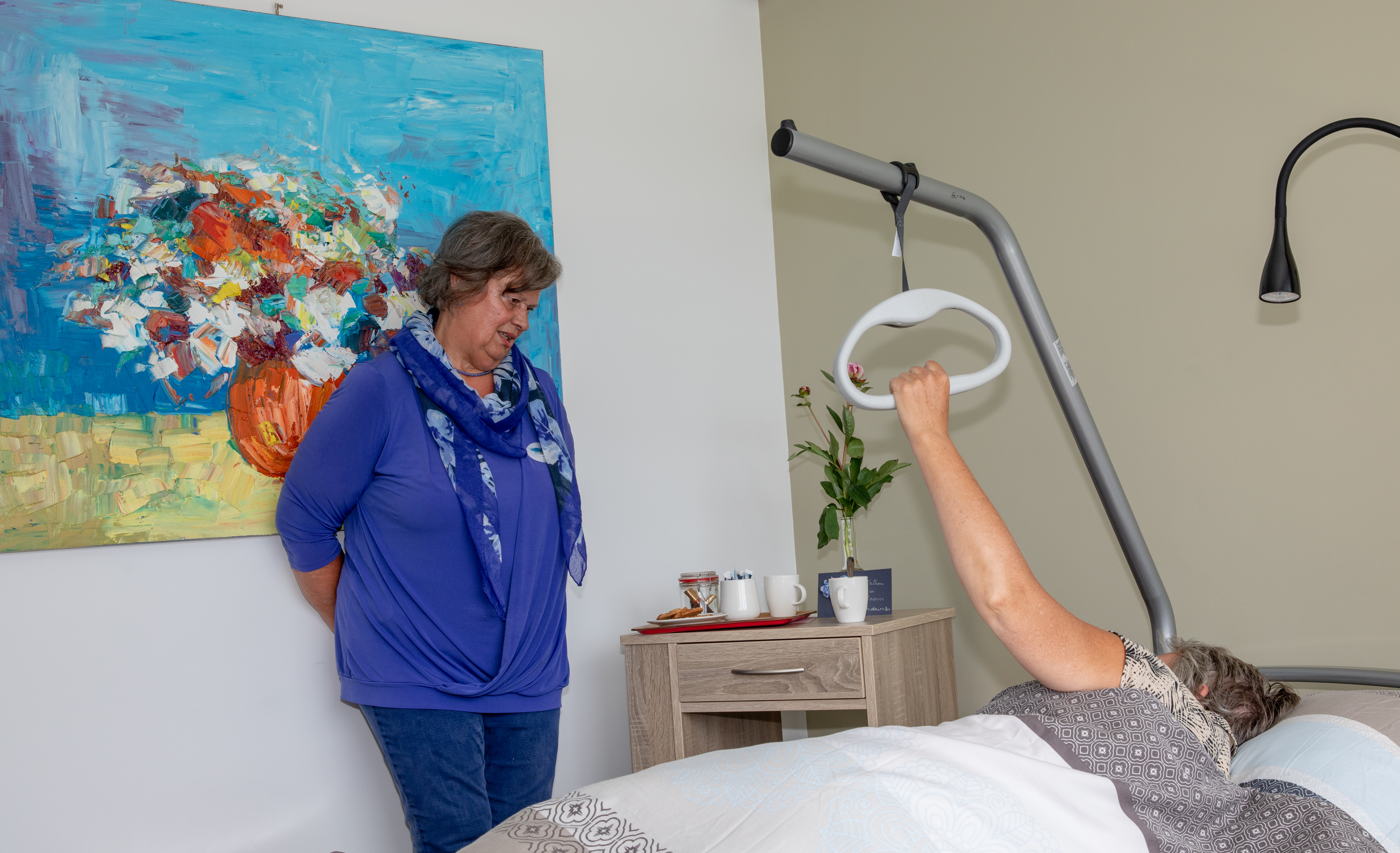 Vrouw praat met een oudere vrouw die in een ziekenhuisbed ligt