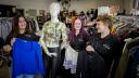 Vrijwilligers van YouthsWEAR houden kleding vast en lachen
