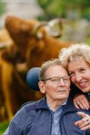 Een mevrouw en een man in een rolstoel poseren voor een weide met grote bizons