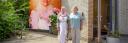 Twee vrouwen van hart voor noord poseren samen voor een muur waarop een van hen is afgebeeld