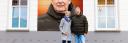 Man en vrouw van Dorpsservicewinkel Gassel poseren voor een muur waarvan de man is afgebeeld met streetart