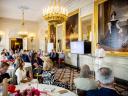 Koningin Máxima presenteert met digibord naast zich voor groep deelnemers die aan tafels zitten