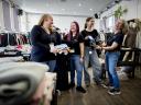 Vrijwilligers van YouthsWEAR houden kleding vast en lachen