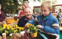 Kind en oudere man planten samen bloemetjes in potgrond